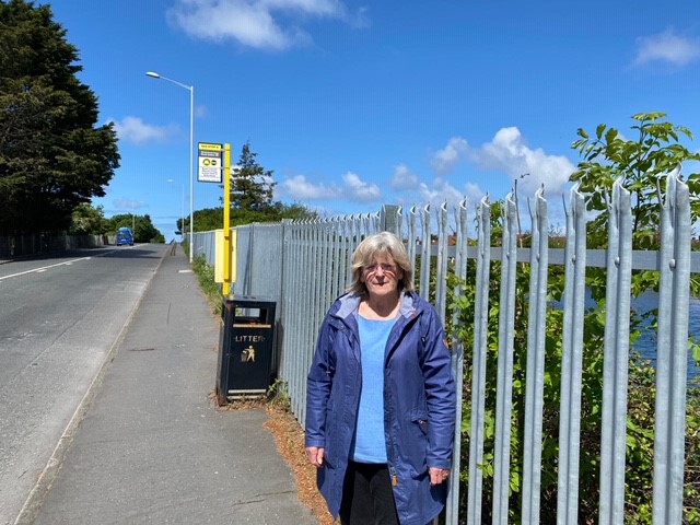 Councillor Wright stands by the fence at Meols Station